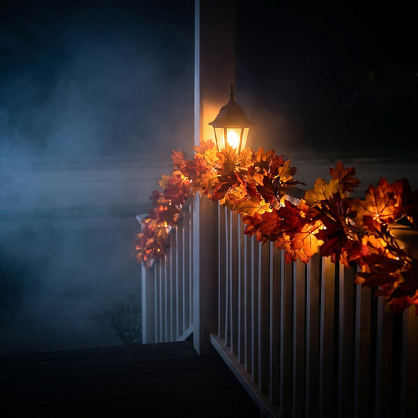 A maple leaf garland along a porch railing under a lantern